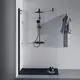 Duschsystem mit transparenten Wänden, schwarzem Thermostat und Handbrause. Handtuch hängt an der Wand, Produkte auf einer Ablage. Ideal Standard ist die Marke.